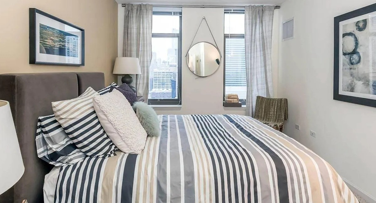 Cozy bedroom featuring a comfortable bed with striped bedding, a large window, and modern decor at Echelon at K Station in Chicago