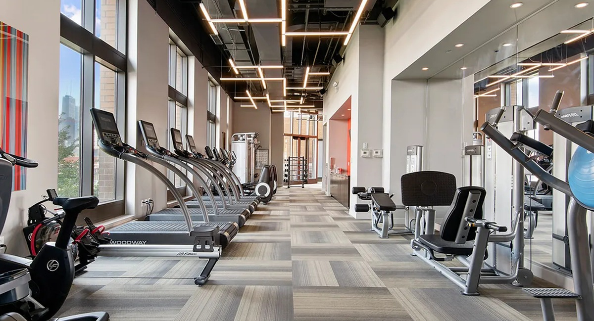 State-of-the-art fitness center with a wide array of cardio equipment and large windows at Echelon at K Station in Chicago