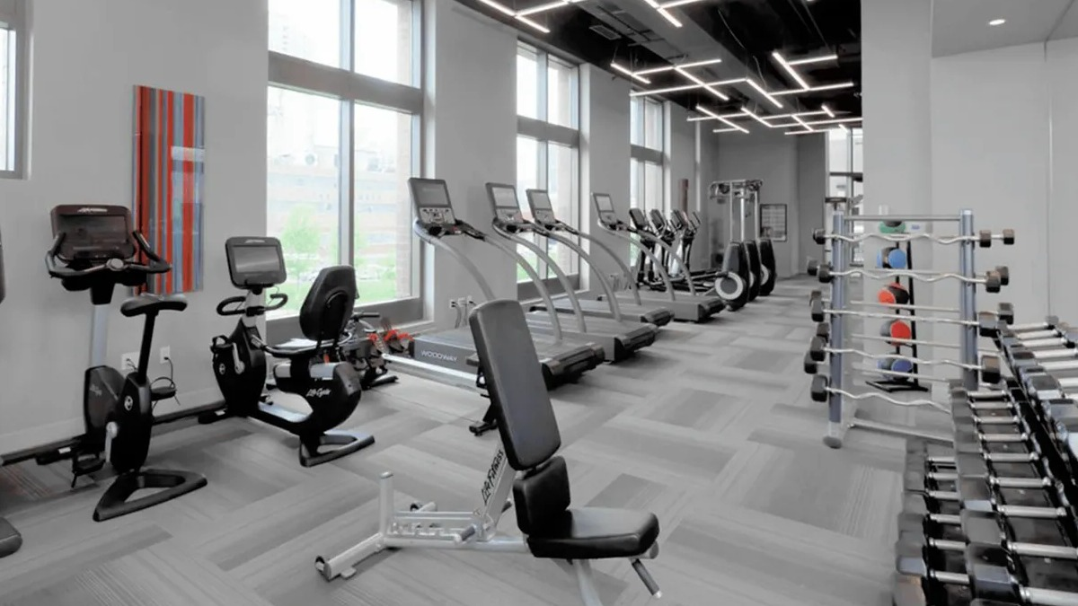Expansive fitness center with a variety of cardio and strength training equipment, bathed in natural light at Echelon at K Station in Chicago