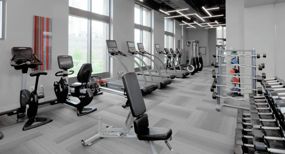 Expansive fitness center with a variety of cardio and strength training equipment, bathed in natural light at Echelon at K Station in Chicago