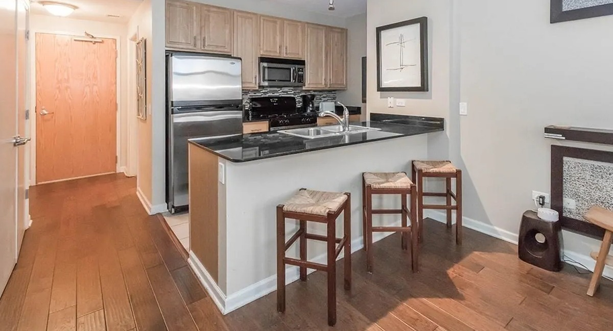 Contemporary kitchen featuring a breakfast bar, stainless steel appliances, and elegant hardwood floors at Echelon at K Station in Chicago