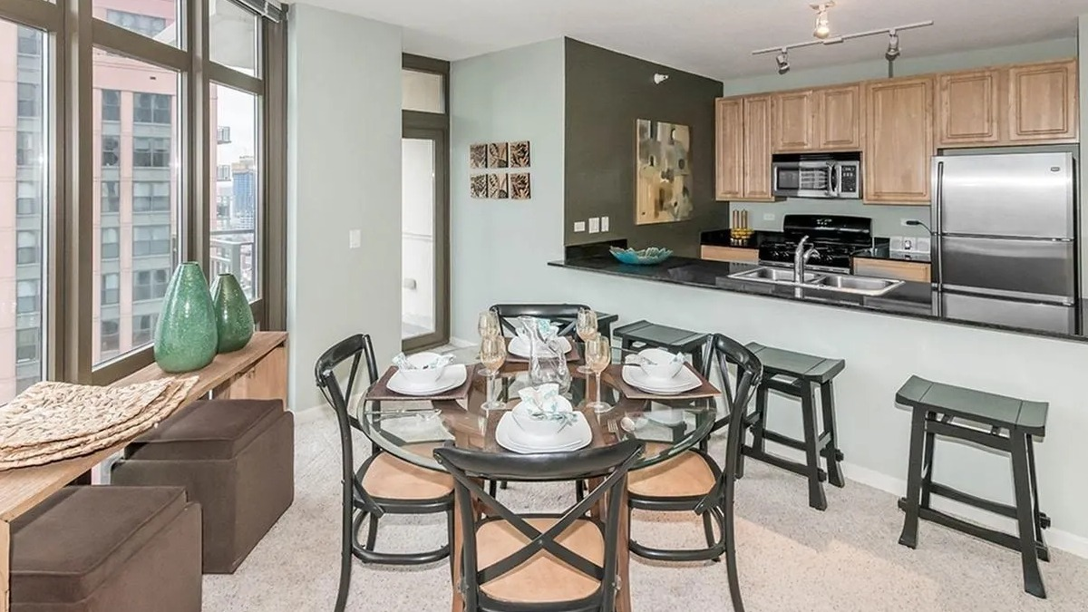 Kitchen and dining area with light wood cabinets, stainless steel appliances, and large windows offering city views at Echelon at K Station in Chicago