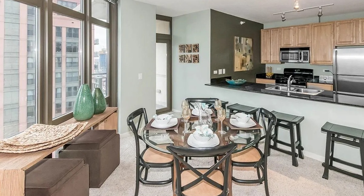 Kitchen and dining area with light wood cabinets, stainless steel appliances, and large windows offering city views at Echelon at K Station in Chicago