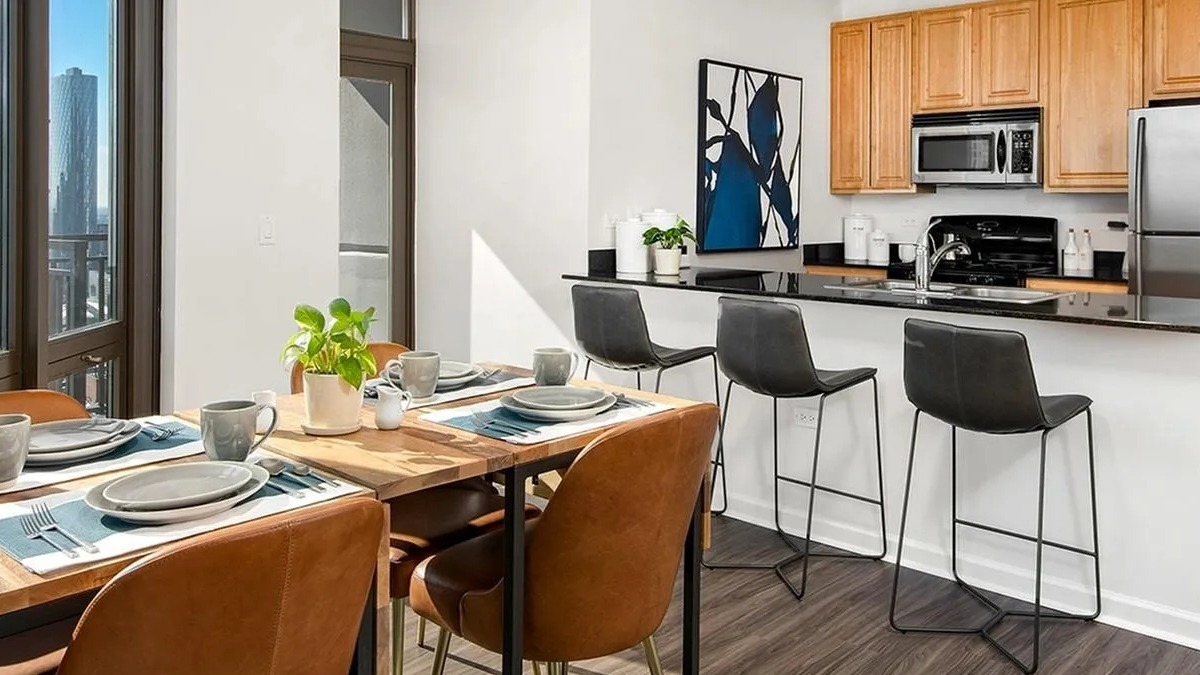 Open-concept kitchen and dining area with a breakfast bar, wooden cabinets, and modern appliances at Echelon at K Station in Chicago