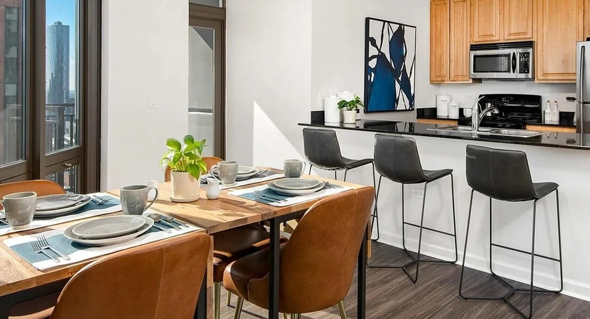 Open-concept kitchen and dining area with a breakfast bar, wooden cabinets, and modern appliances at Echelon at K Station in Chicago