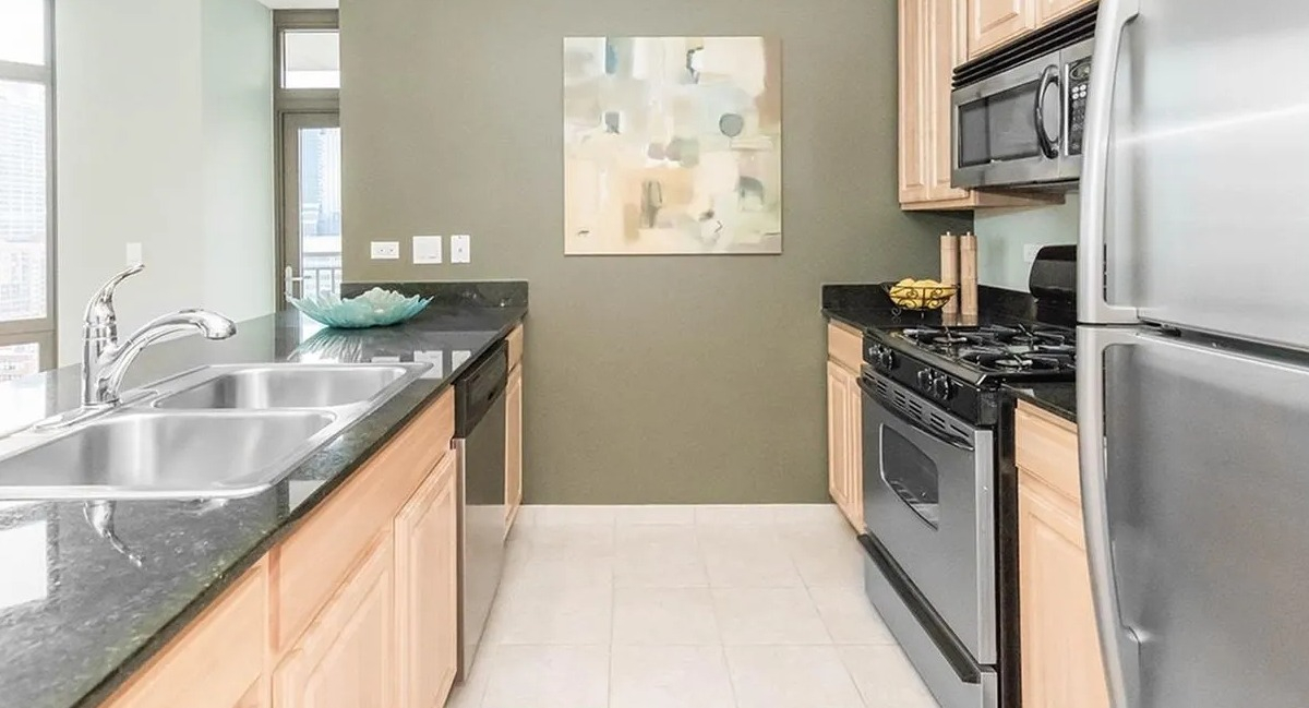 Functional kitchen with light wood cabinets, stainless steel appliances, and ample counter space at Echelon at K Station in Chicago