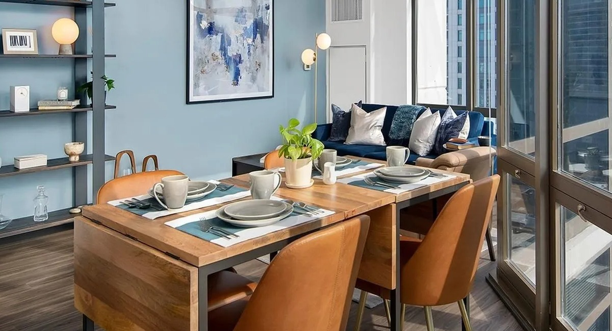 Modern open-concept living and dining area with city views through large windows at Echelon at K Station in Chicago