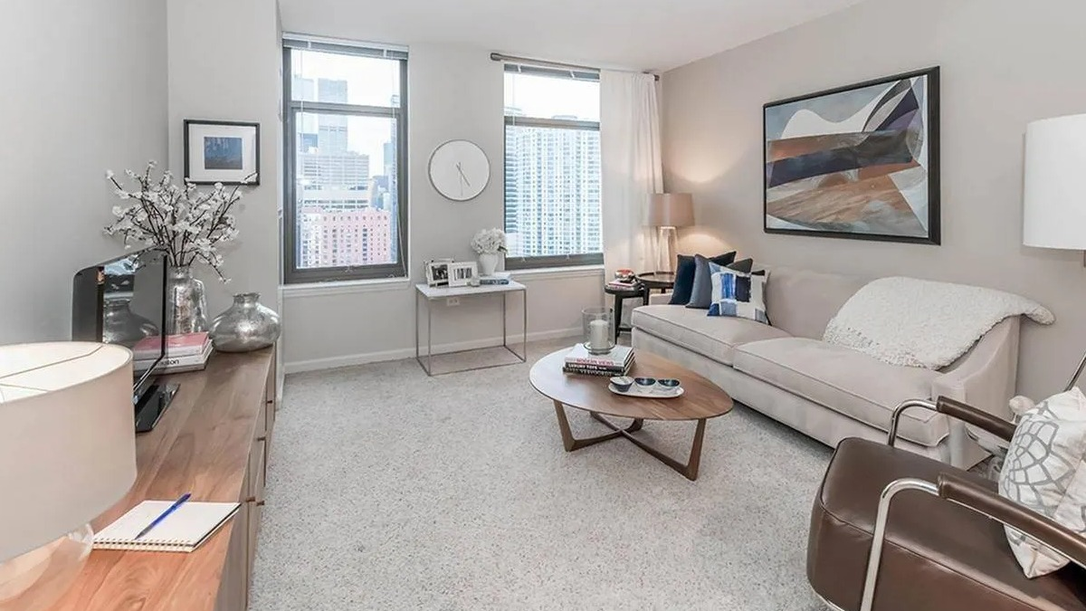Bright and spacious living room with a comfortable sofa, armchair, and large windows at Echelon at K Station in Chicago
