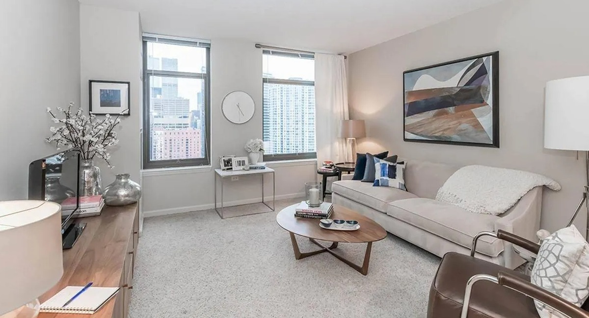 Bright and spacious living room with a comfortable sofa, armchair, and large windows at Echelon at K Station in Chicago