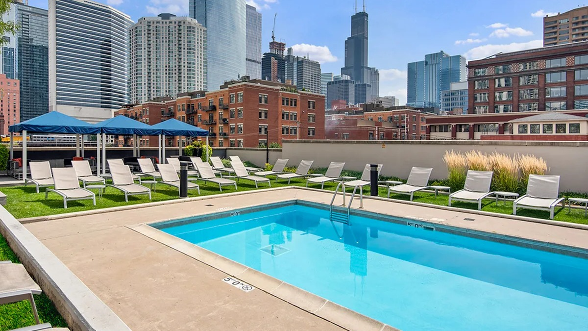 Beautiful outdoor swimming pool with lounge chairs and stunning city skyline views at Echelon at K Station in Chicago