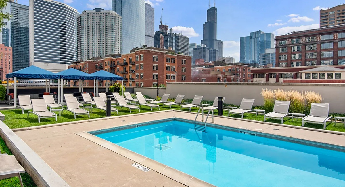 Beautiful outdoor swimming pool with lounge chairs and stunning city skyline views at Echelon at K Station in Chicago
