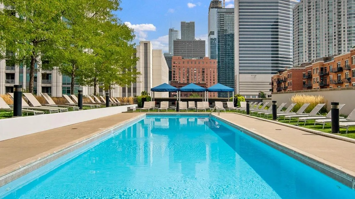Sparkling outdoor swimming pool surrounded by lounge chairs with a vibrant city skyline backdrop at Echelon at K Station in Chicago