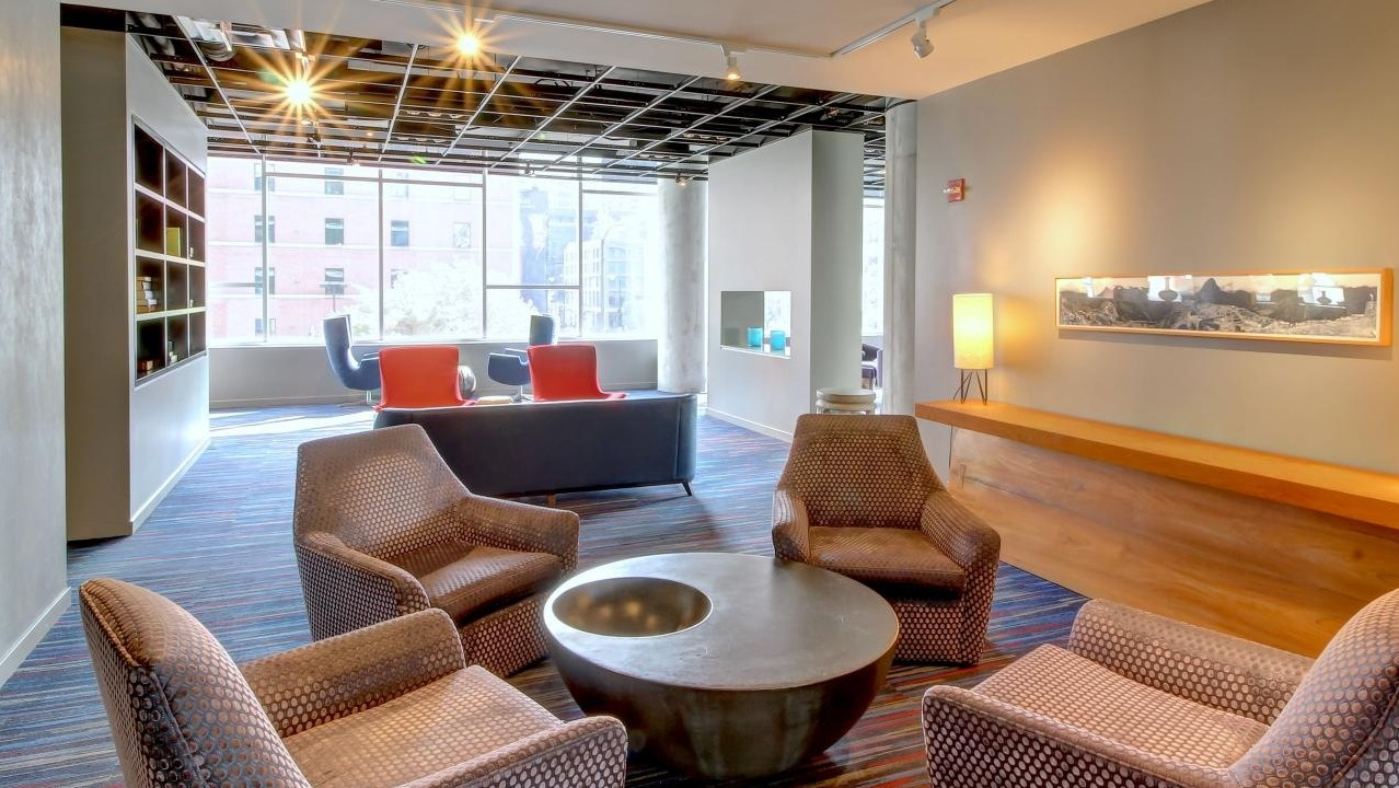 Inviting resident gathering space with patterned armchairs, a circular coffee table, and bright lighting at Eight O Five Apartments in Chicago