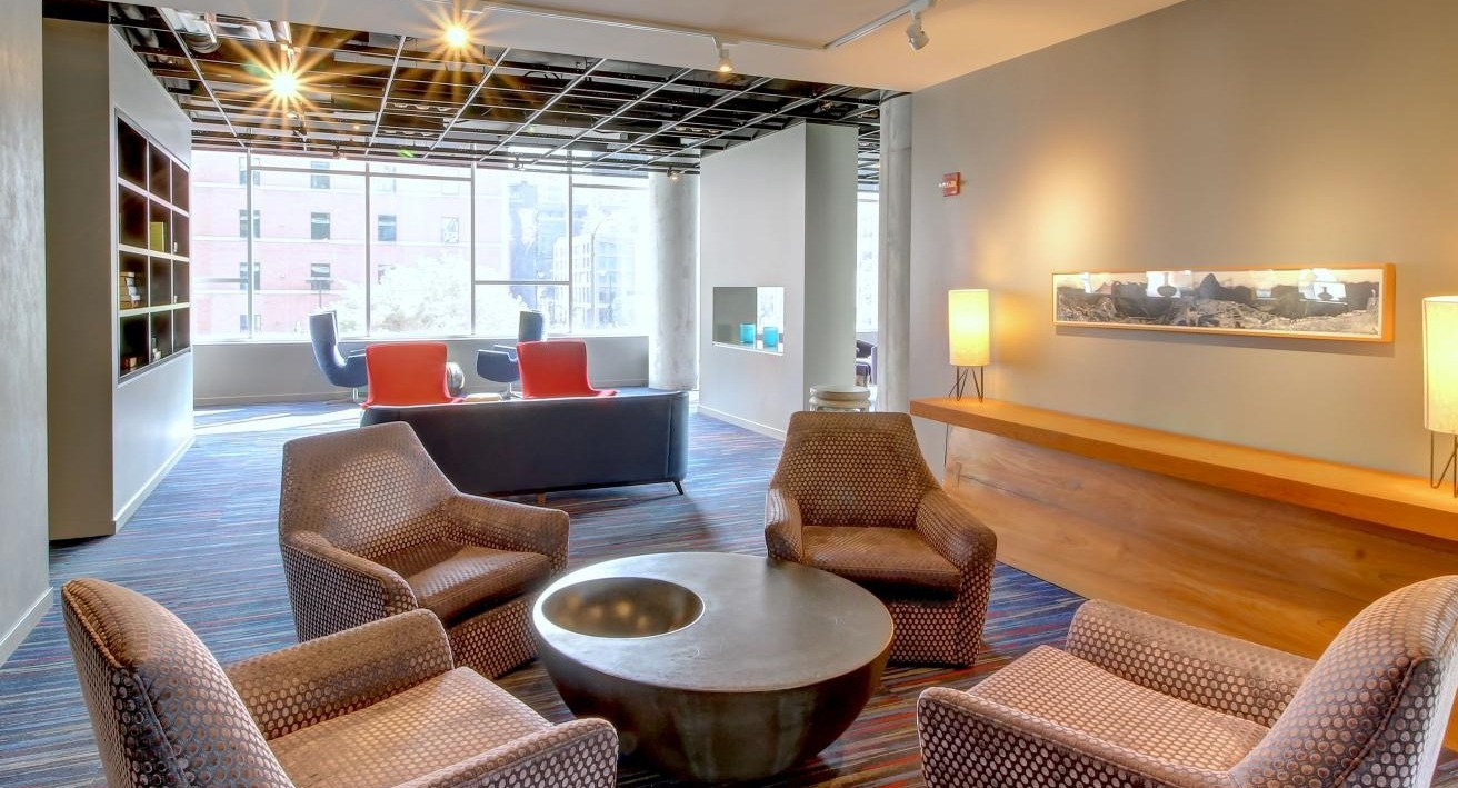 Inviting resident gathering space with patterned armchairs, a circular coffee table, and bright lighting at Eight O Five Apartments in Chicago