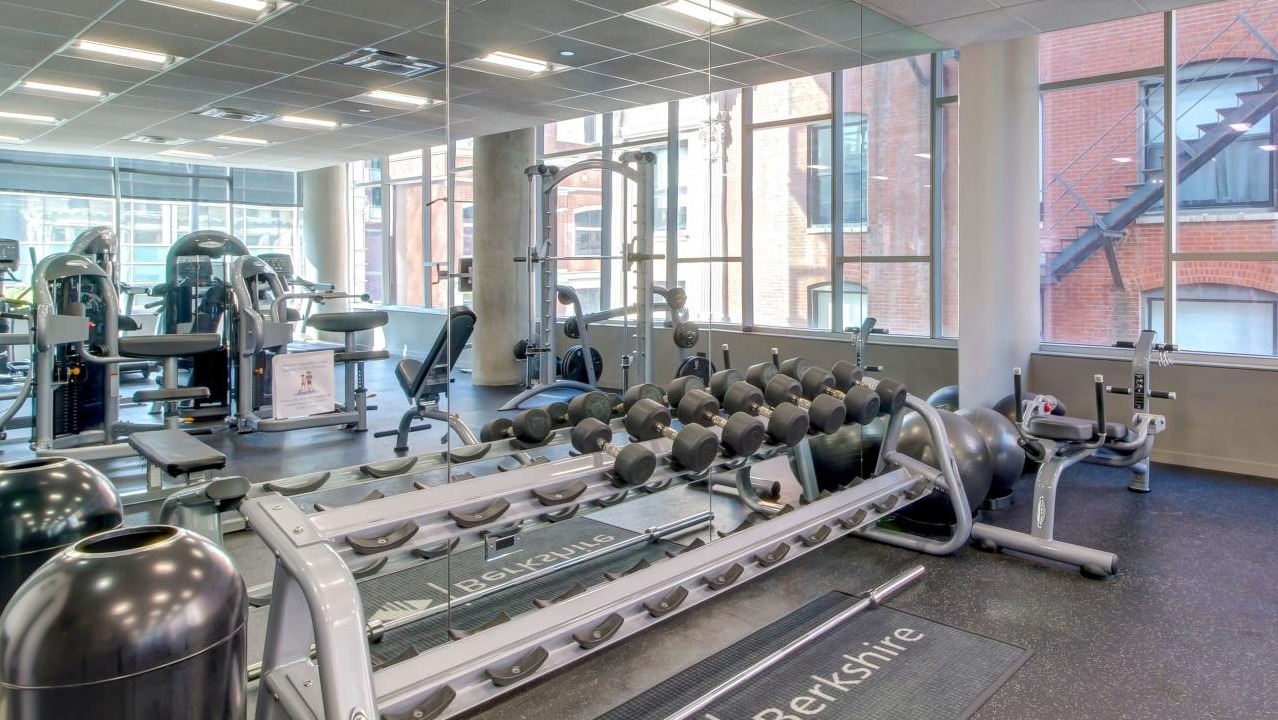 Comprehensive fitness center with various weight machines, free weights, and large mirrors for workouts at Eight O Five Apartments in Chicago