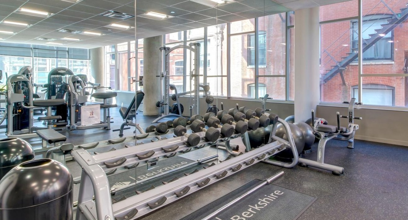 Comprehensive fitness center with various weight machines, free weights, and large mirrors for workouts at Eight O Five Apartments in Chicago