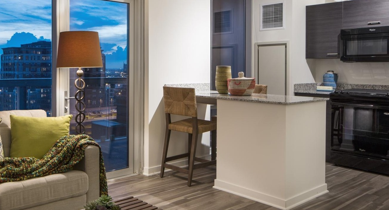 Open-concept kitchen and living room combo with a breakfast bar, dark cabinetry, and city views at Eight O Five