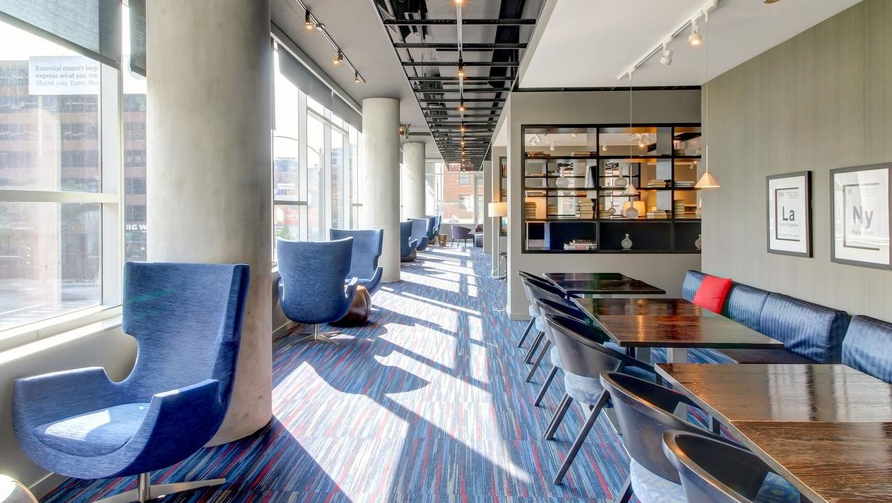 Stylish resident lounge and co-working space with blue chairs, long tables, and large windows at Eight O Five in Chicago