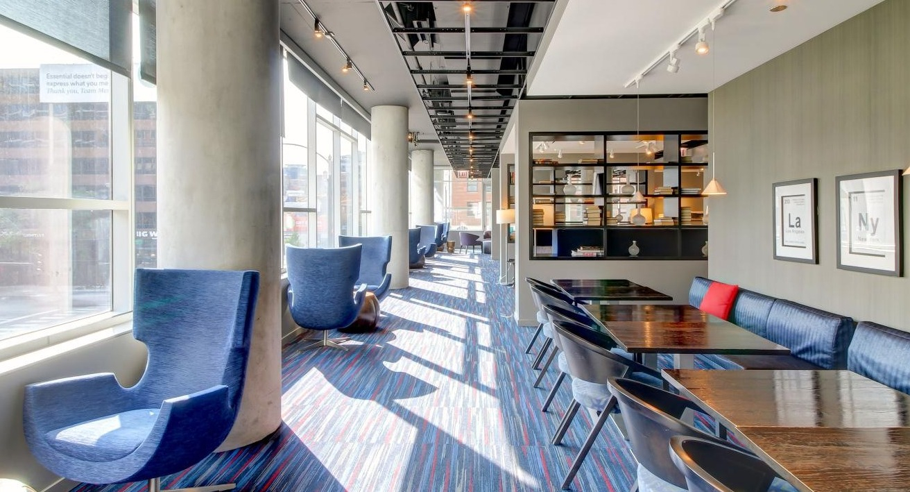 Stylish resident lounge and co-working space with blue chairs, long tables, and large windows at Eight O Five in Chicago