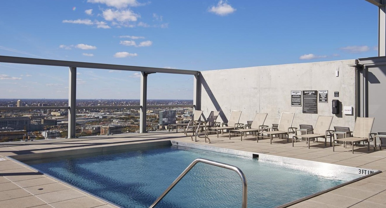Serene rooftop swimming pool with lounge chairs, offering stunning panoramic views of the city skyline at Eight O Five Apartments in Chicago