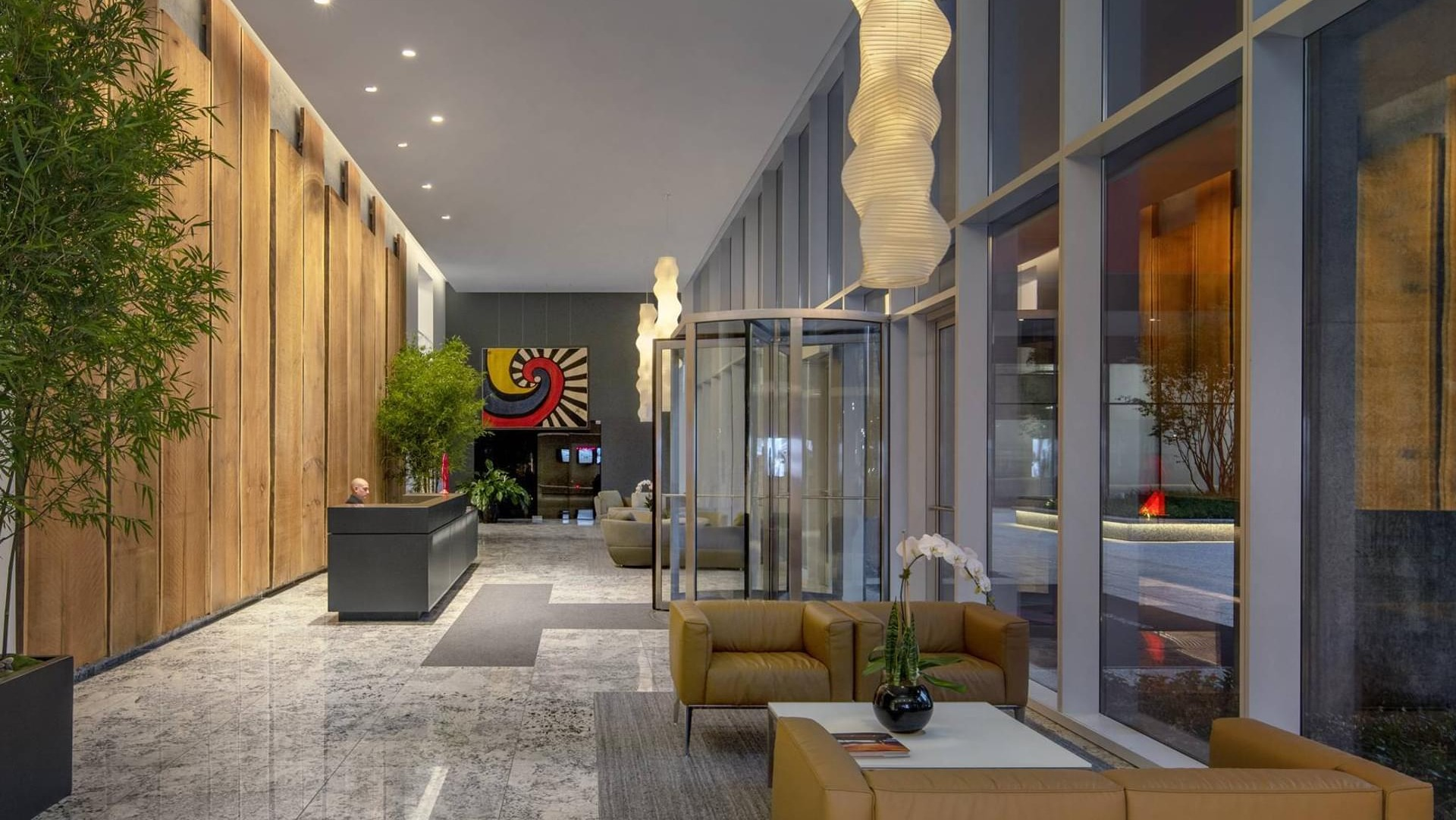 Elegant apartment lobby with warm wood panels, modern lighting, indoor greenery, and stylish lounge seating at Optima Signature in Chicago