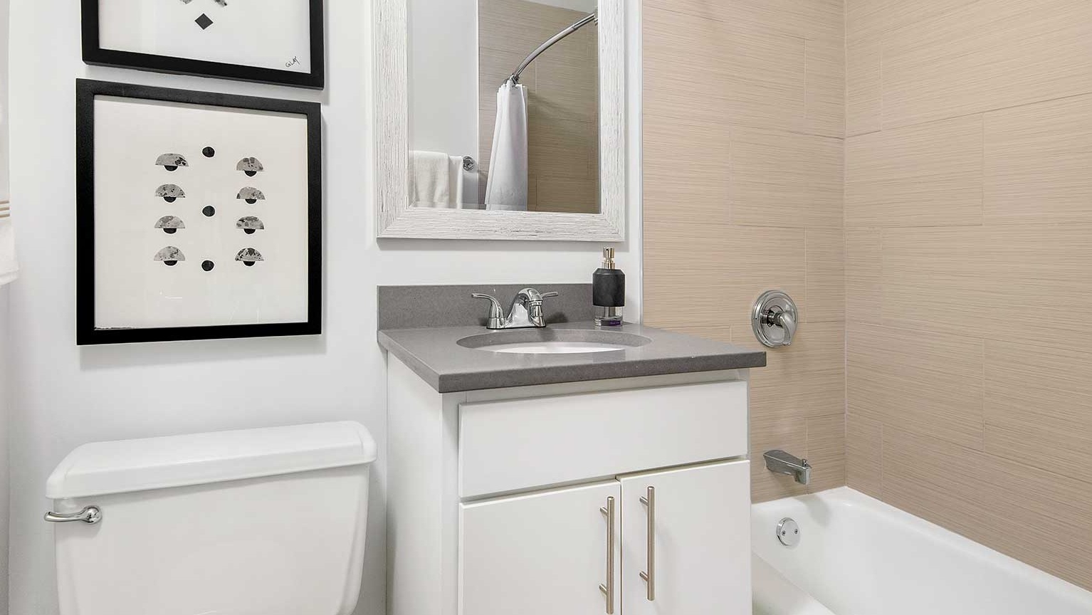 Modern bathroom with a single vanity, a well-lit mirror, and a clean bathtub and shower combo at Eleven Thirty apartments in Chicago