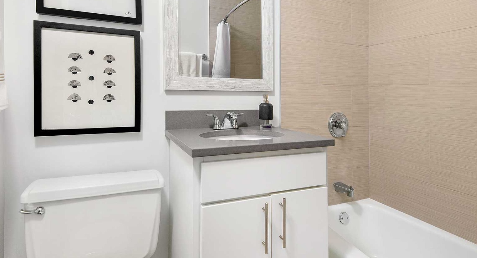 Modern bathroom with a single vanity, a well-lit mirror, and a clean bathtub and shower combo at Eleven Thirty apartments in Chicago