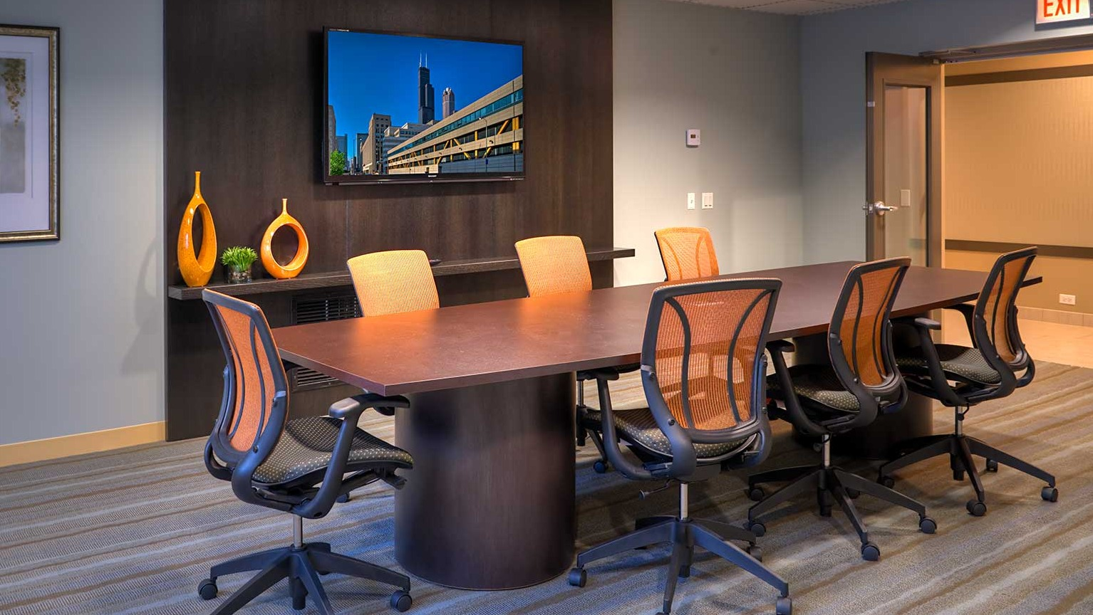 Modern conference room with a large table, ergonomic chairs, and a wall-mounted TV for meetings at Eleven Thirty apartments in Chicago