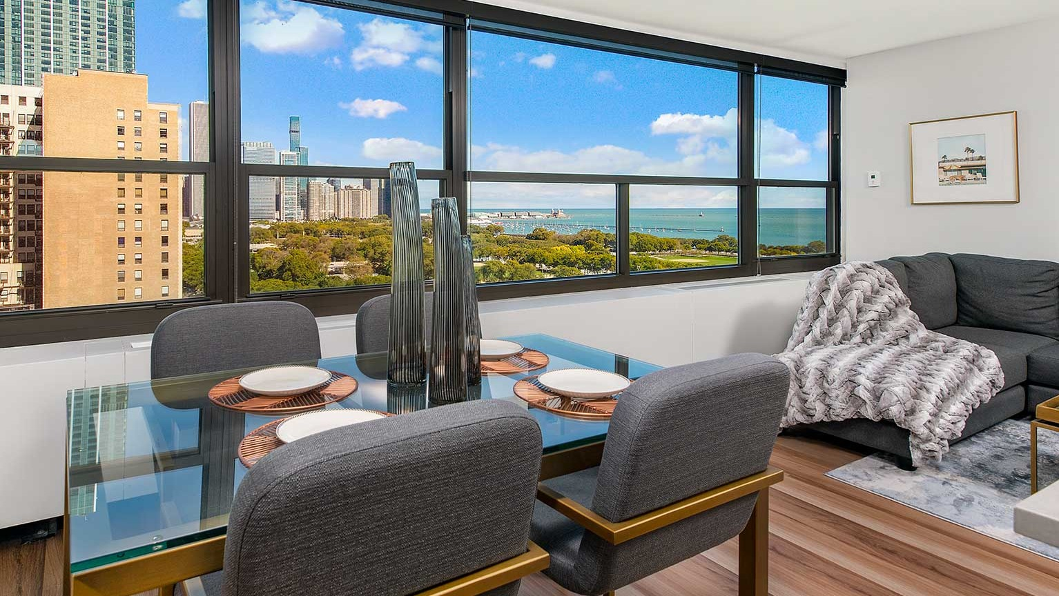 Elegant dining room with a glass table and upholstered chairs, offering stunning lake and city views at Eleven Thirty apartments in Chicago