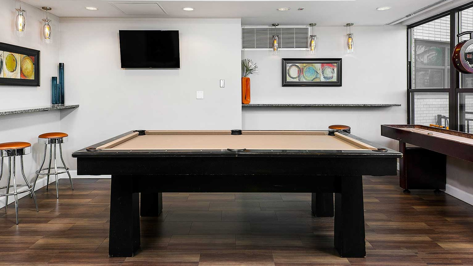 Fun game room featuring a billiards table, shuffleboard, and bar seating, perfect for entertainment at Eleven Thirty apartments in Chicago