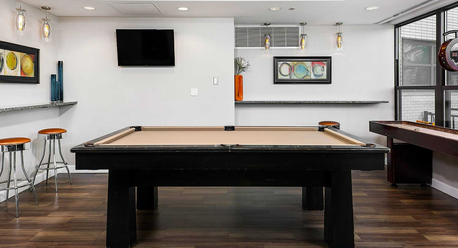 Fun game room featuring a billiards table, shuffleboard, and bar seating, perfect for entertainment at Eleven Thirty apartments in Chicago