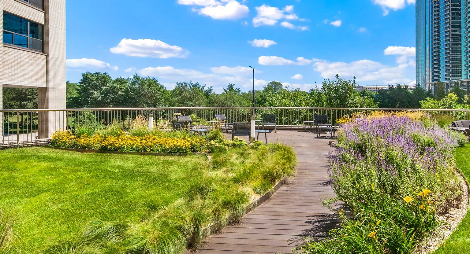 Beautifully landscaped outdoor courtyard with a winding wooden path, lush greenery, and comfortable seating areas at Eleven Thirty in Chicago