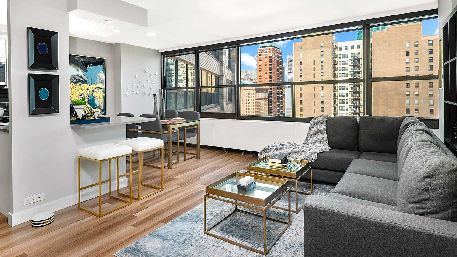 Chic living room with a large sectional sofa, coffee tables, and a breakfast bar with modern stools, at Eleven Thirty apartments in Chicago