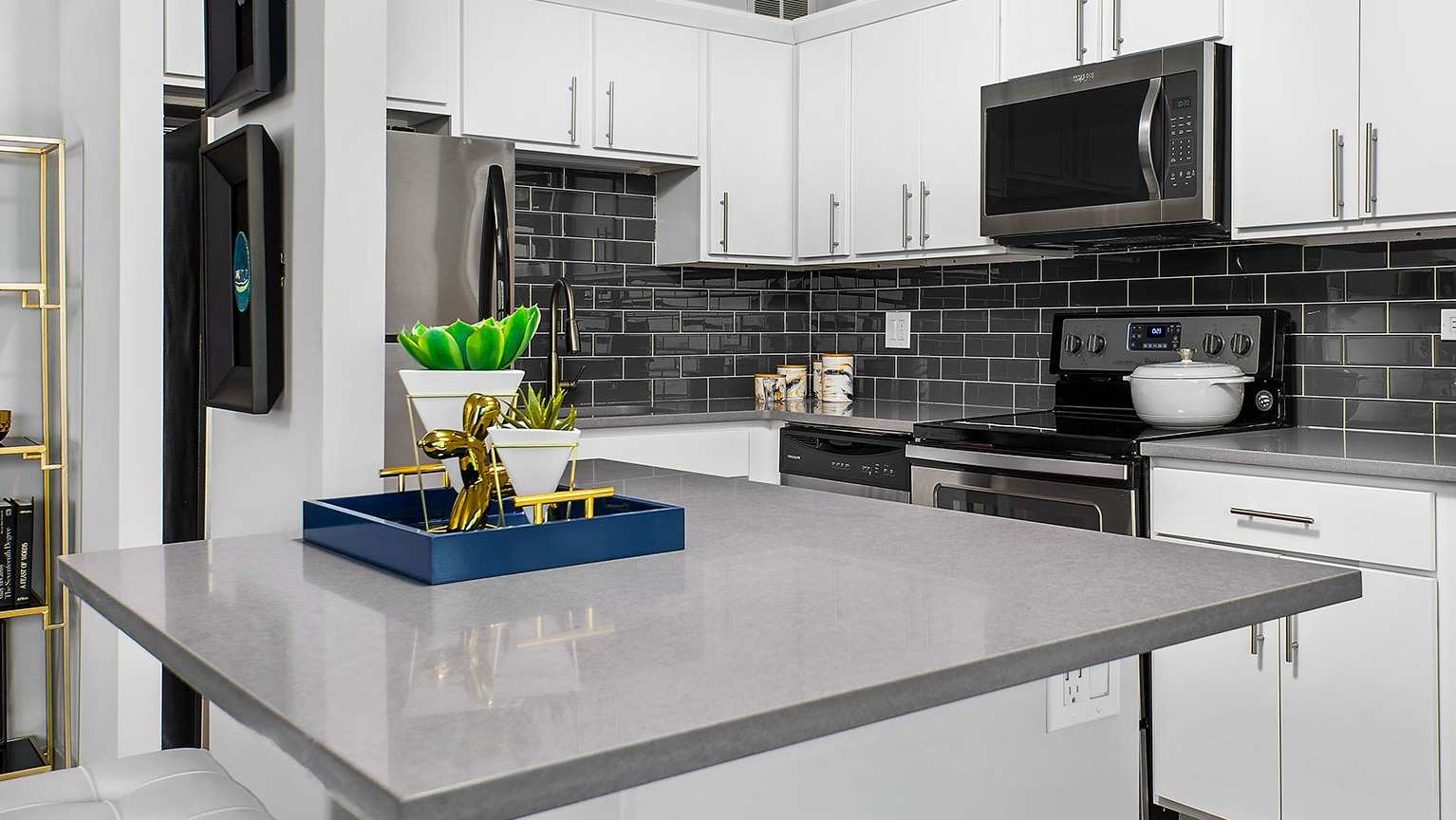 Contemporary kitchen with white cabinets, dark subway tile backsplash, stainless steel appliances, and a central island at Eleven Thirty in Chicago