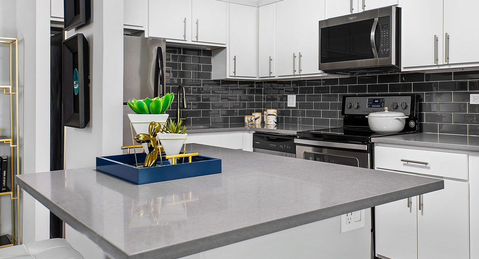 Contemporary kitchen with white cabinets, dark subway tile backsplash, stainless steel appliances, and a central island at Eleven Thirty in Chicago