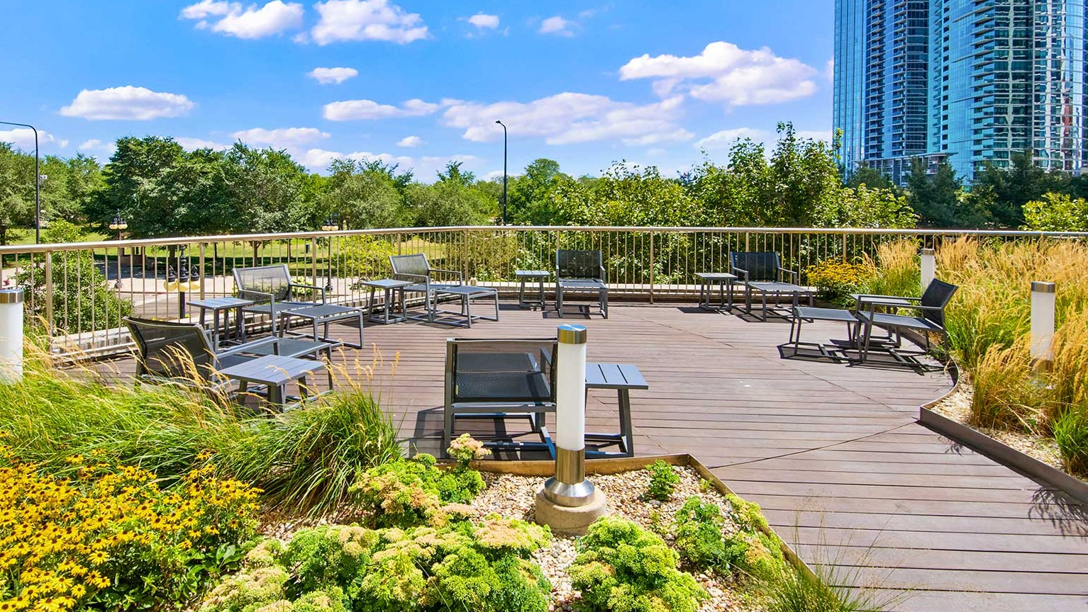 Spacious outdoor deck with various seating arrangements, surrounded by vibrant plants, offering cityscape views at Eleven Thirty in Chicago