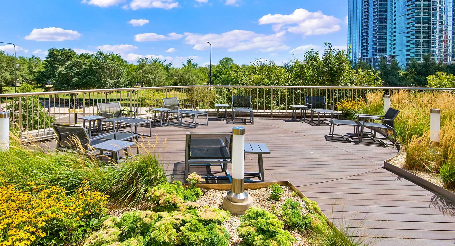 Spacious outdoor deck with various seating arrangements, surrounded by vibrant plants, offering cityscape views at Eleven Thirty in Chicago