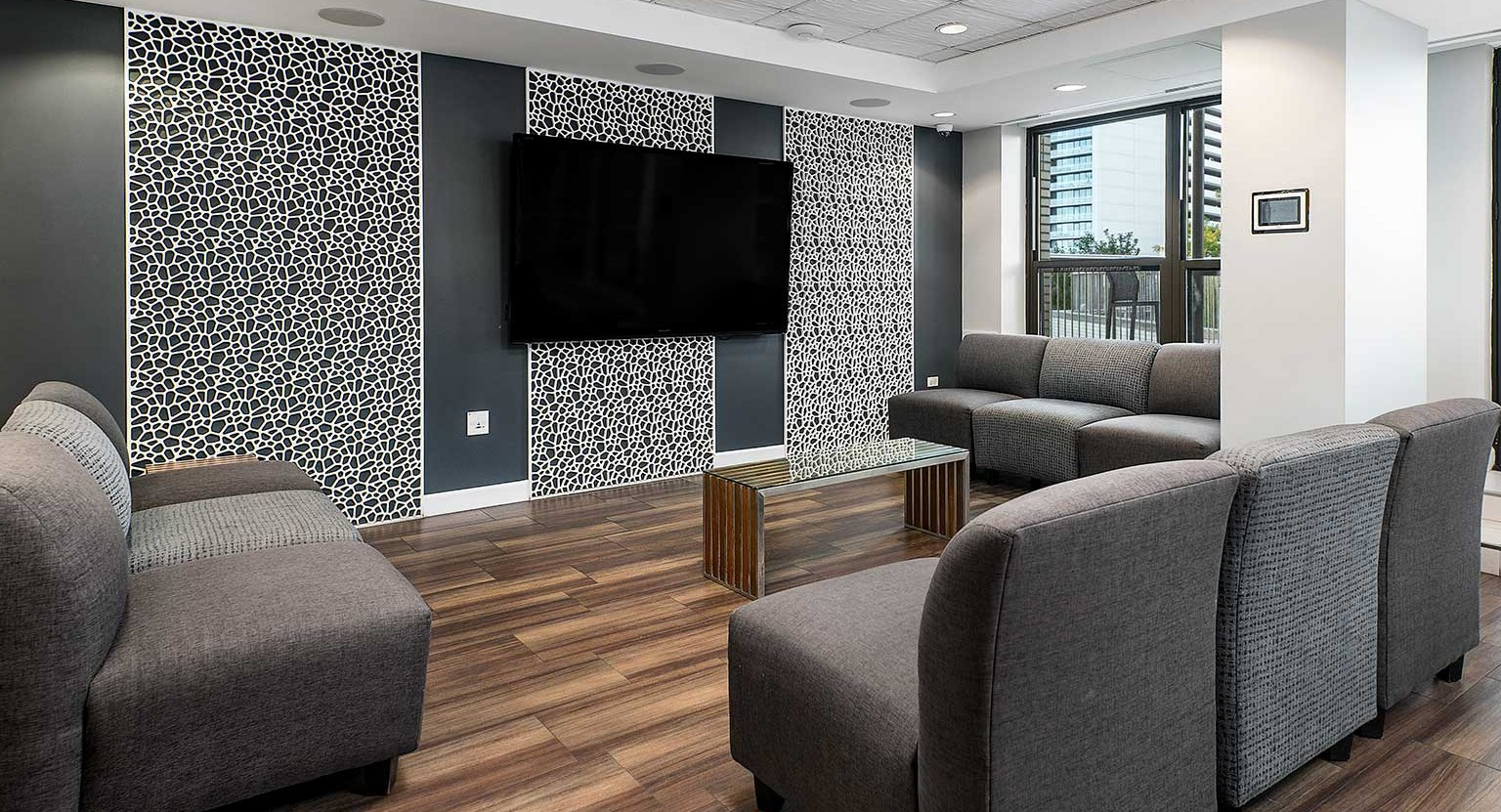 Comfortable resident lounge with plush seating, a large wall-mounted TV, and modern decor at Eleven Thirty apartments in Chicago