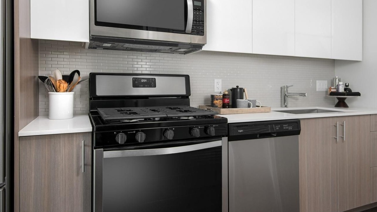 Contemporary apartment kitchen with stainless steel appliances, white quartz countertops, and a subway tile backsplash at Eleven40 in Chicago