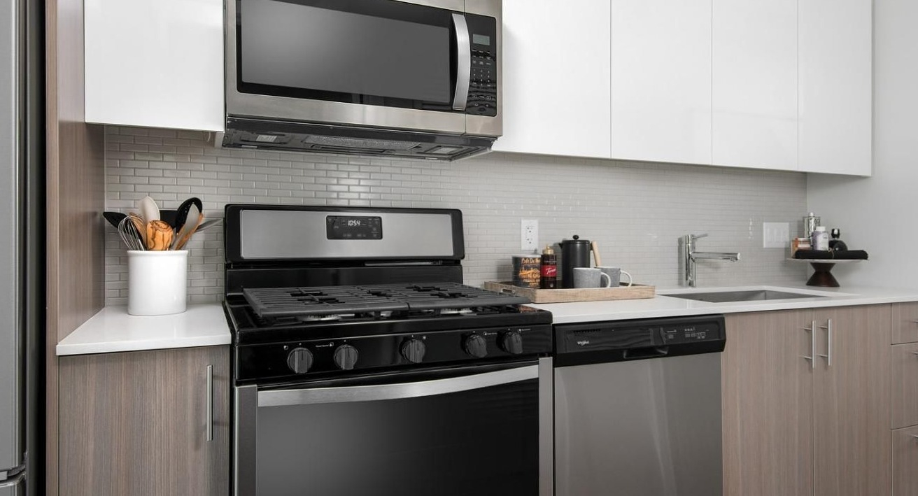 Contemporary apartment kitchen with stainless steel appliances, white quartz countertops, and a subway tile backsplash at Eleven40 in Chicago