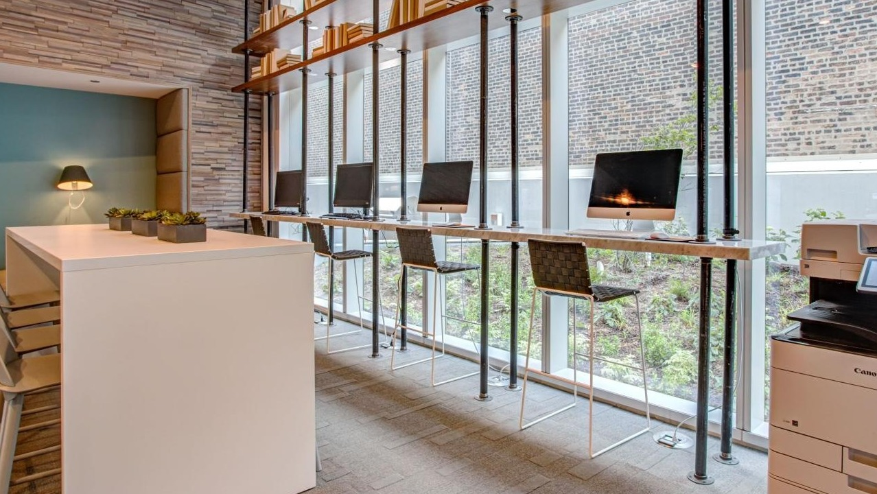 Productive co-working space with individual computer stations, high-top seating, and a multi-function printer at Eleven40 apartments in Chicago