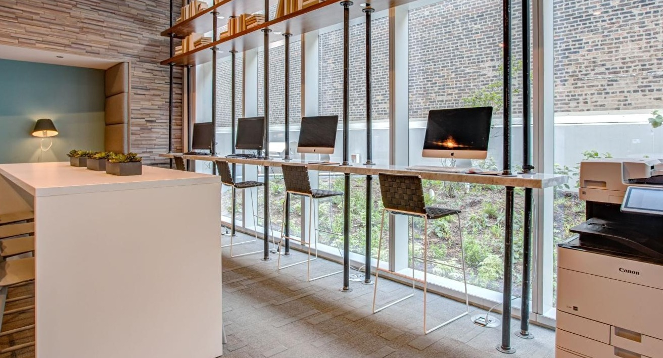 Productive co-working space with individual computer stations, high-top seating, and a multi-function printer at Eleven40 apartments in Chicago
