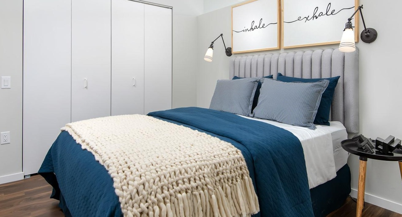 Cozy apartment bedroom with a comfortable bed, stylish blue bedding, and a large closet at Eleven40 apartments in Chicago