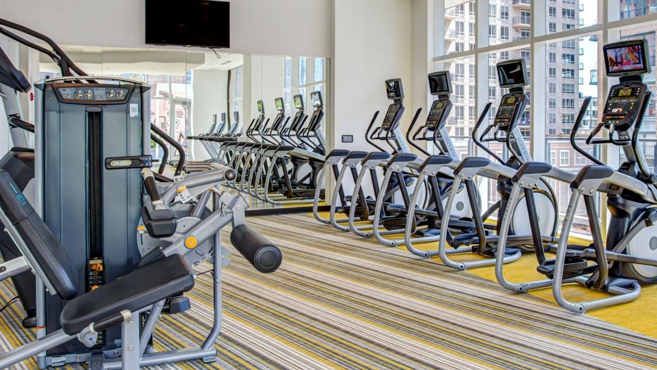 State-of-the-art fitness center with a variety of cardio machines, strength equipment, and large windows at Eleven40 apartments in Chicago