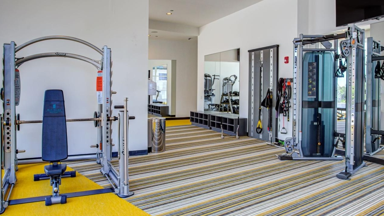 Spacious gym area with weight training equipment, including a squat rack and functional trainer, at Eleven40 apartments in Chicago