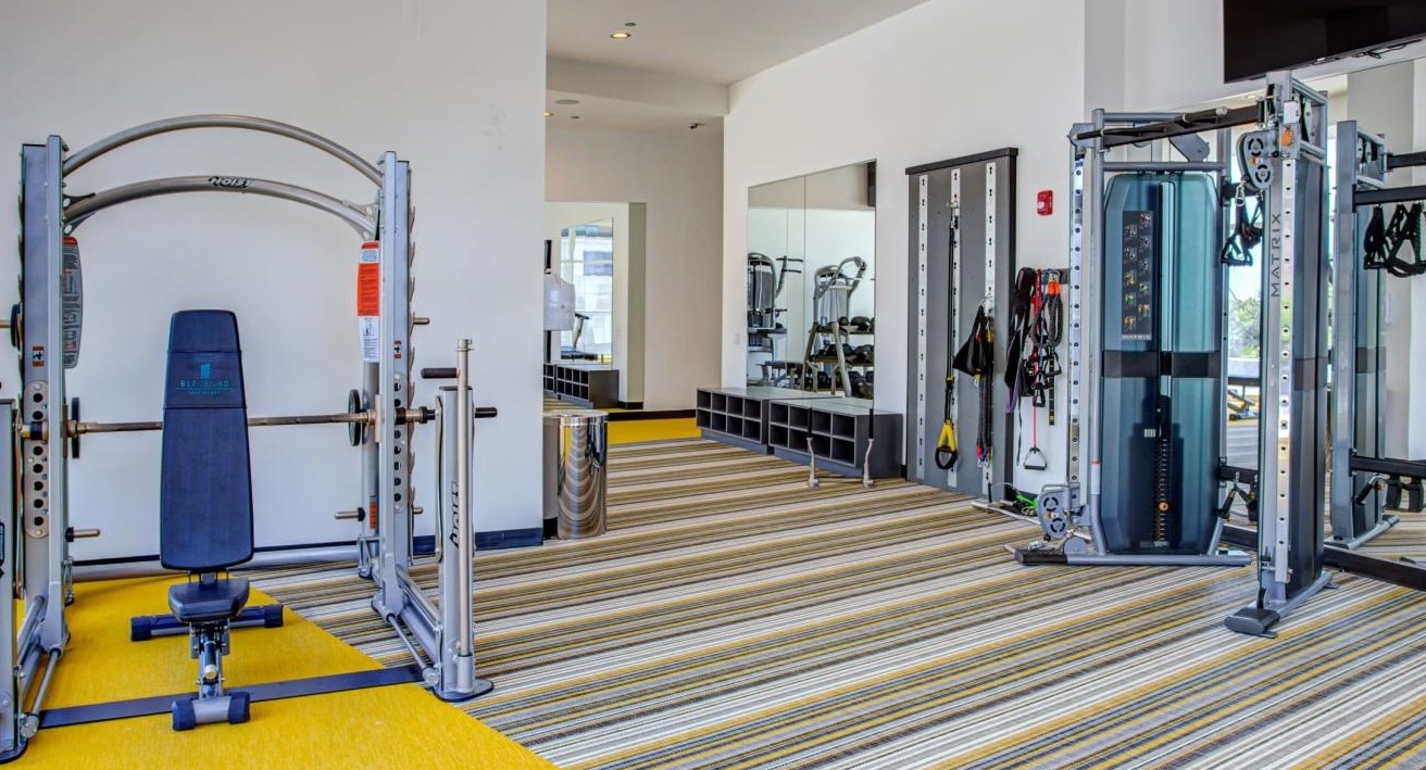 Spacious gym area with weight training equipment, including a squat rack and functional trainer, at Eleven40 apartments in Chicago