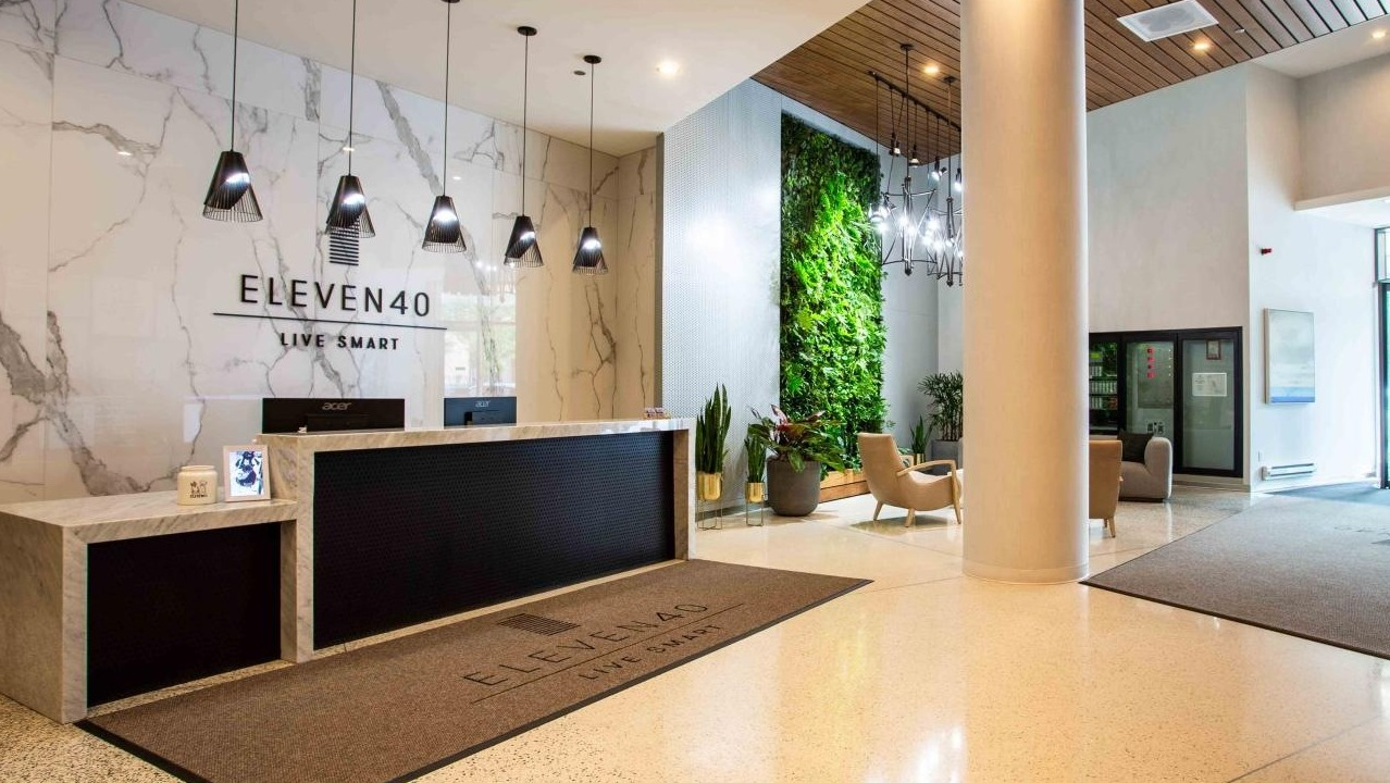 Elegant Eleven40 apartment lobby with a stylish reception desk, a living wall, and modern seating, welcoming residents and guests in Chicago