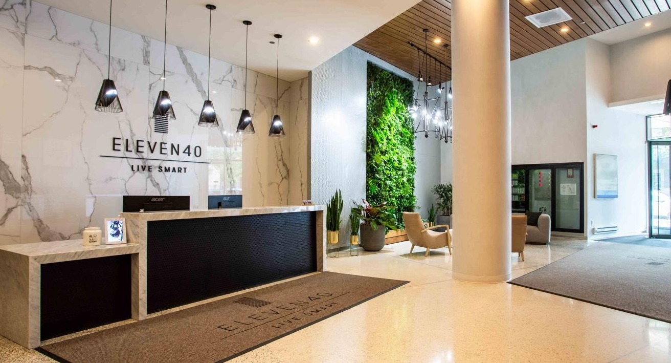Elegant Eleven40 apartment lobby with a stylish reception desk, a living wall, and modern seating, welcoming residents and guests in Chicago