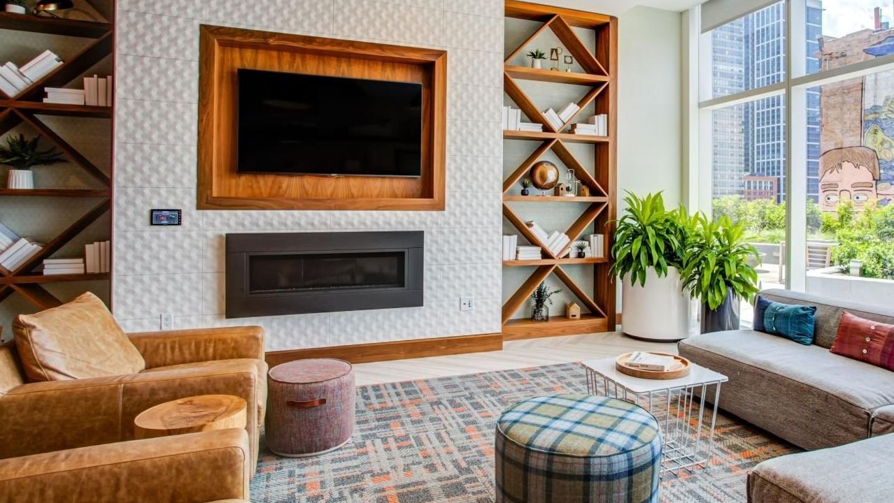 Cozy resident lounge with a fireplace, stylish built-in bookshelves, comfortable seating, and large windows at Eleven40 apartments in Chicago