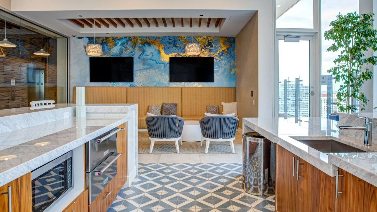 Stylish resident lounge with a modern kitchen island, comfortable seating areas, and a vibrant accent wall at Eleven40 apartments in Chicago